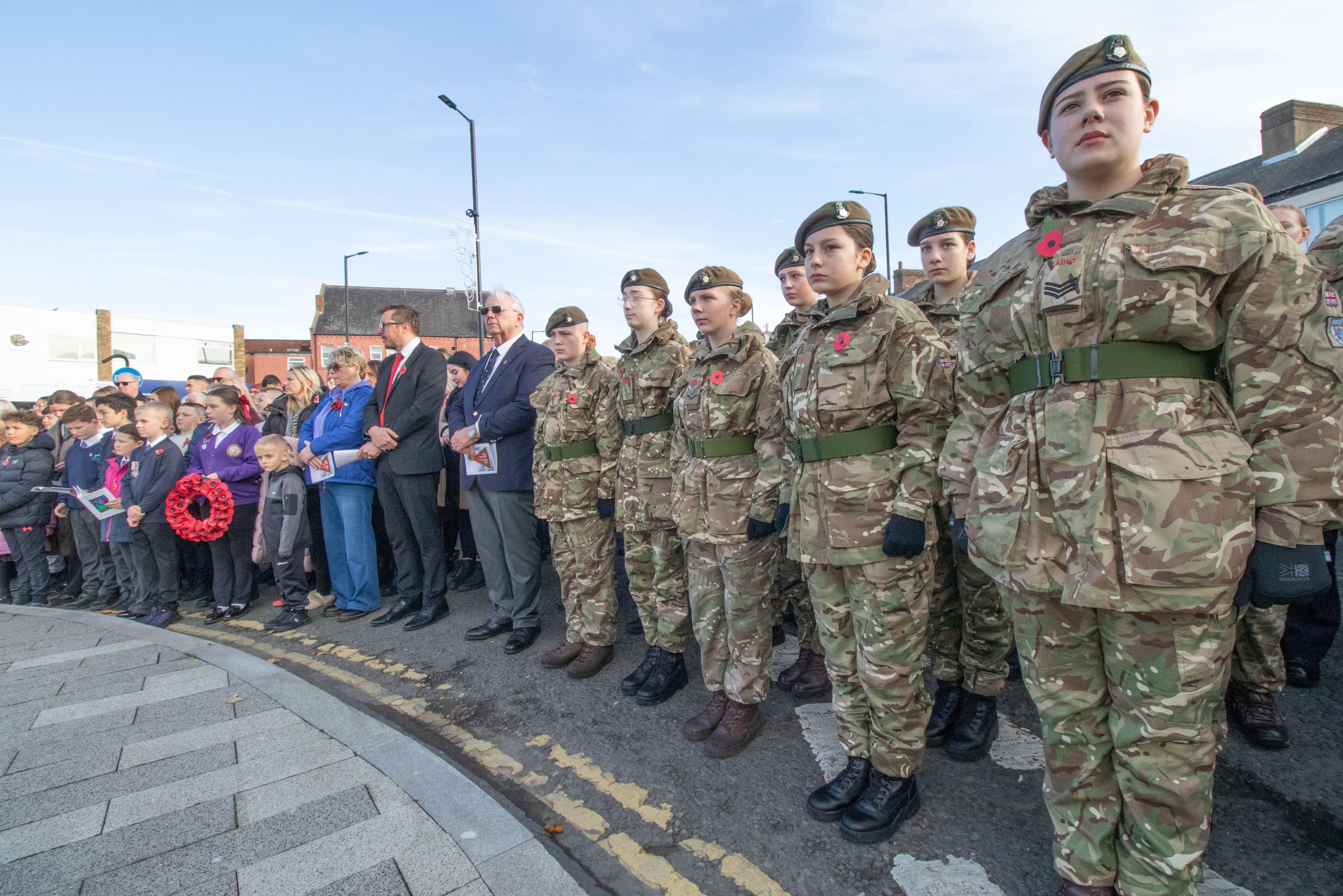 Young people in military camouflage uniforms and berets standing with an elderly man