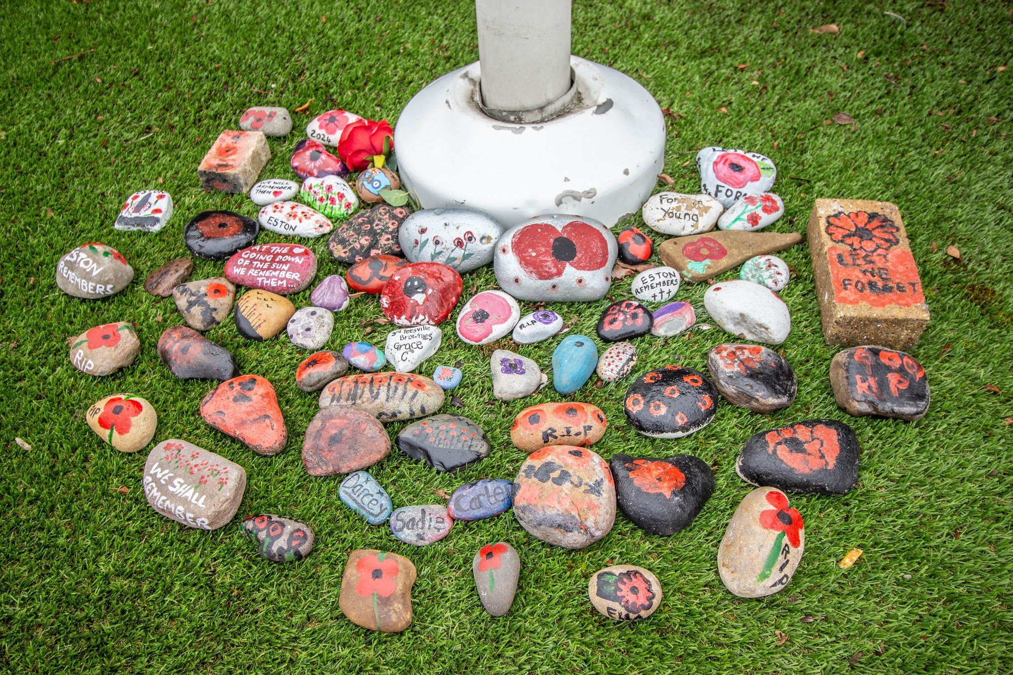 Colourful painted stones arranged around the memorial lamp post