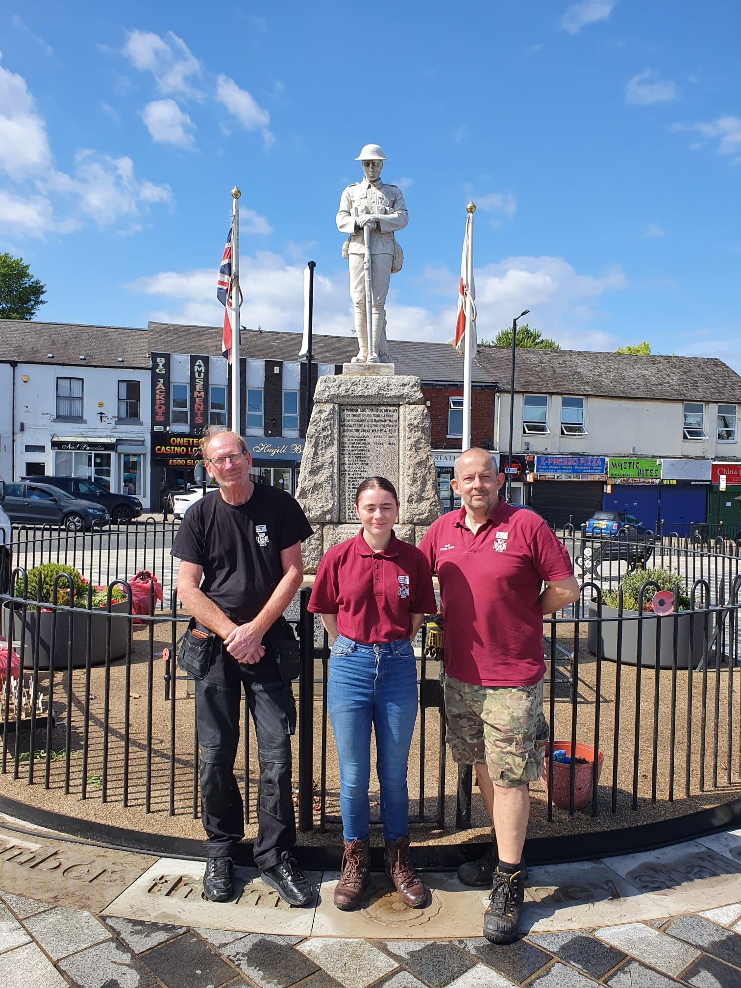 Three people standing in front of the Eston war memorial